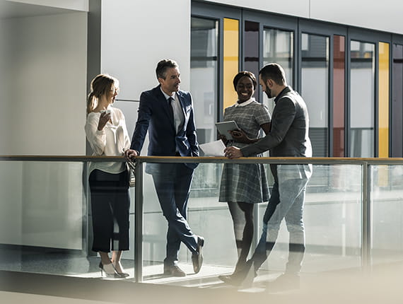 Group of young businesspeople standing chatting on office balcony