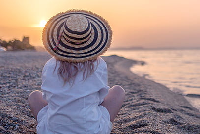 Woman sitting on the beach at sunset