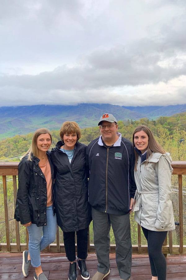 group on a viewing deck in front of mountains and clouds
