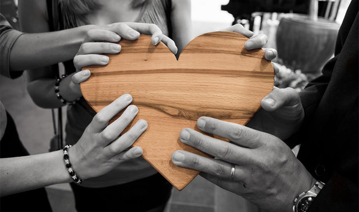 Hands holding a wooden heart
