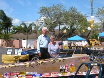 A man and woman posting behind a soapbox racecar.