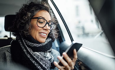 Mature businesswoman using phone while traveling by a taxi
