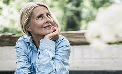 Mature woman sitting on terrace, with cherries on table