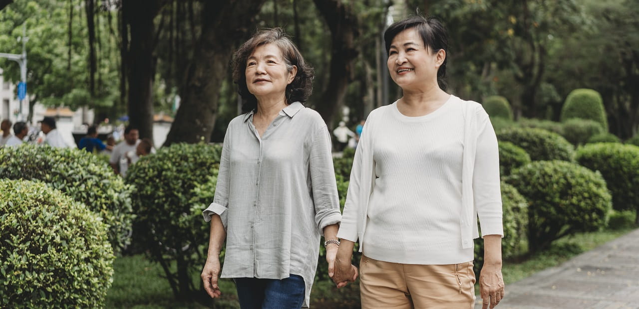 Elderly couple holds hands and walks through a garden