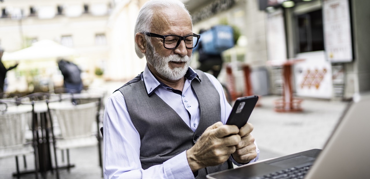 Senior businessman in a cafe looking at his smart phone.