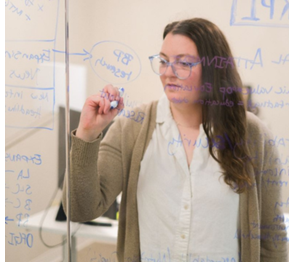 Employee from Slingshot brainstorms ideas on a glass board.