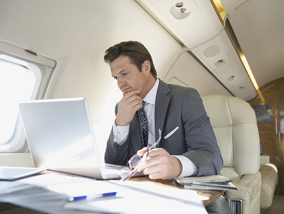 Male executive works on laptop in lear jet