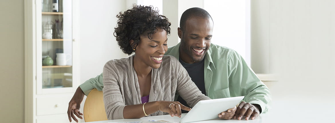 A couple sitting down at a table looking at a paper.