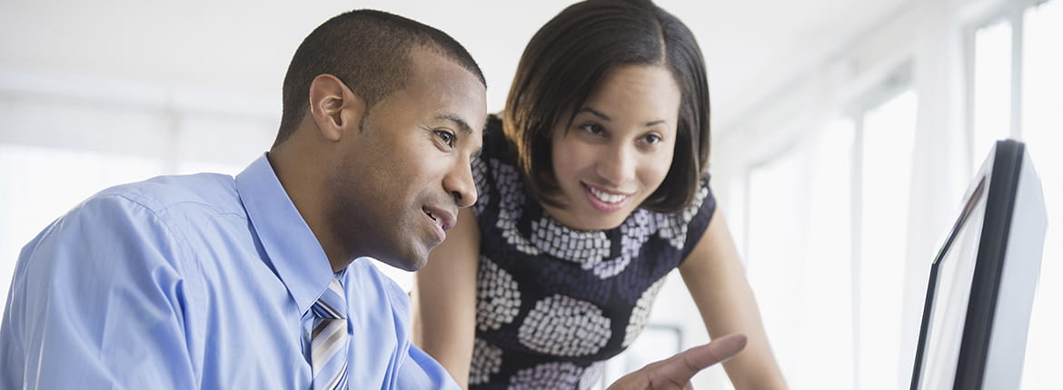 Two people looking at a computer monitor.