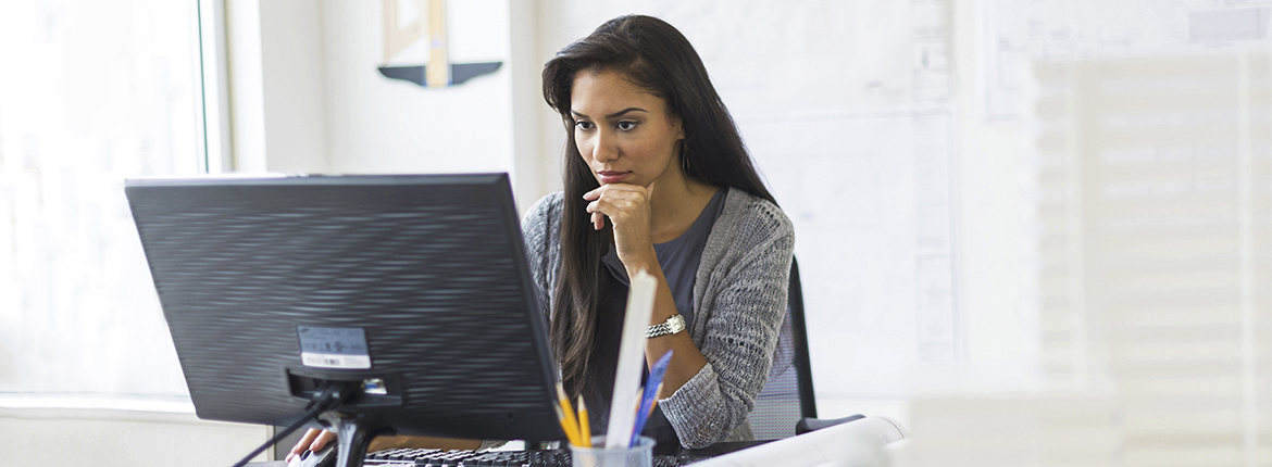 A woman sitting down at a desk using her computer.