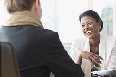 Black businesswoman smiling talking to Caucasion businesswoman