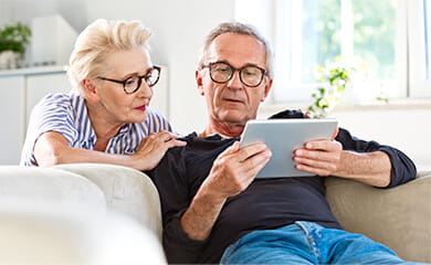 Senior couple watching digital tablet together at home