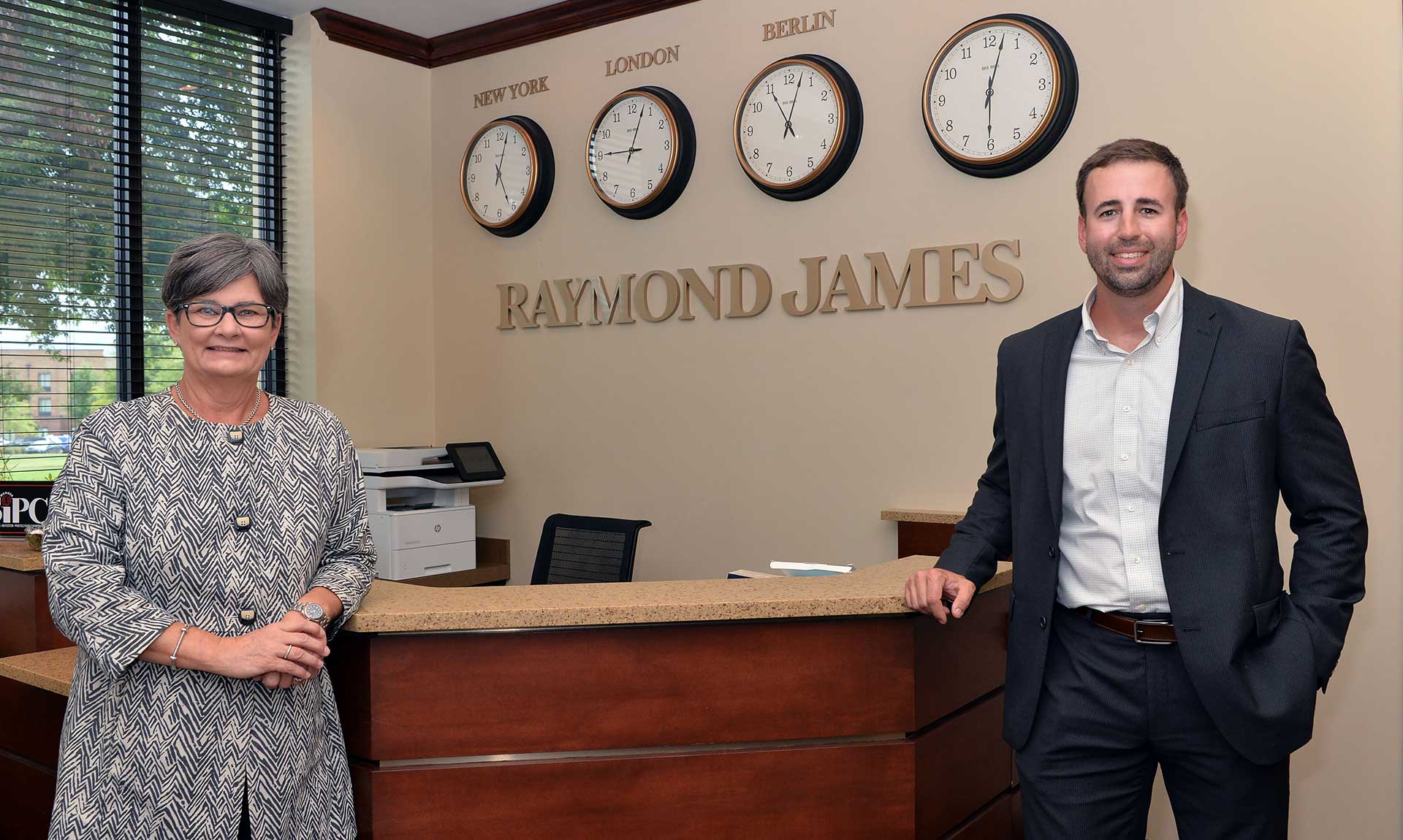 Gary and Nancy in front of Raymond James sign and Clocks