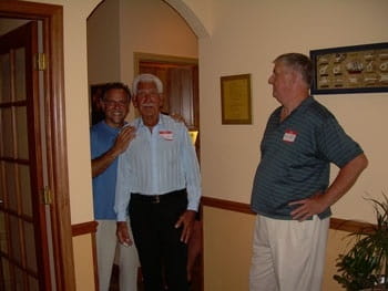 Two men posing for a picture inside a building with another man looking on.