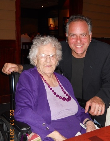 A woman in purple, seated with David standing and posing to her right.