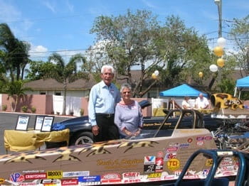 A man and woman posting behind a soapbox racecar.