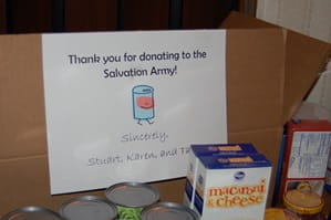 Salvation Army food box with various canned and boxed food items in front.