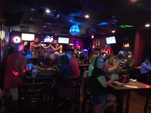 Crowd of people in darkened interior of sports bar