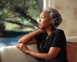 A grey-haired woman looking pensively out the window.