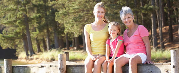 Meet Carol - woman sitting on a pier with daughter and granddaughter