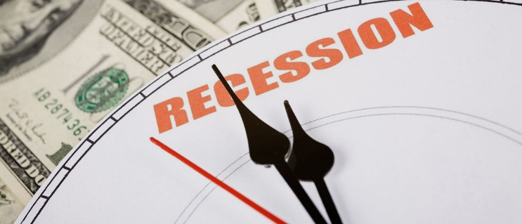 Stock photo of a clock's hands over the word recession with money in the background