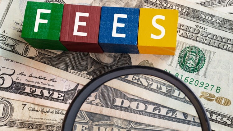 the word fees spelled in colored blocks sitting on american cash