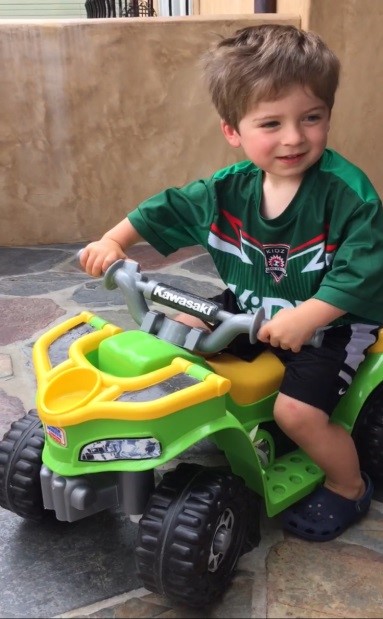 Lowen riding a big wheel.