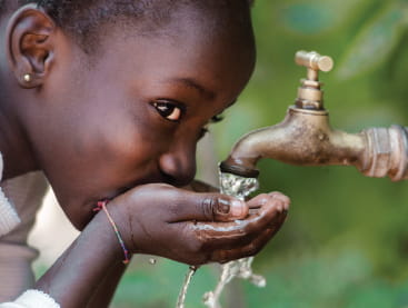 A child drinking water from a spigot.