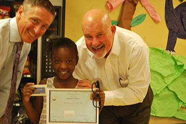 Zach Scott and Scott Schiewe of Transamerica present the first place winner Gabriella with her award certificate and Wal-Mart gift card.