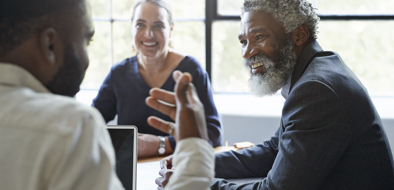 Businessman speaks with two other professionals in an office.