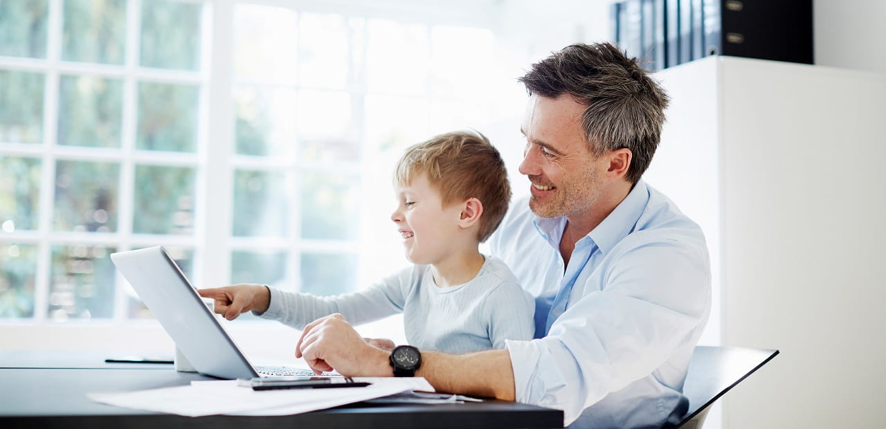 A man and his young son look at a laptop together. 