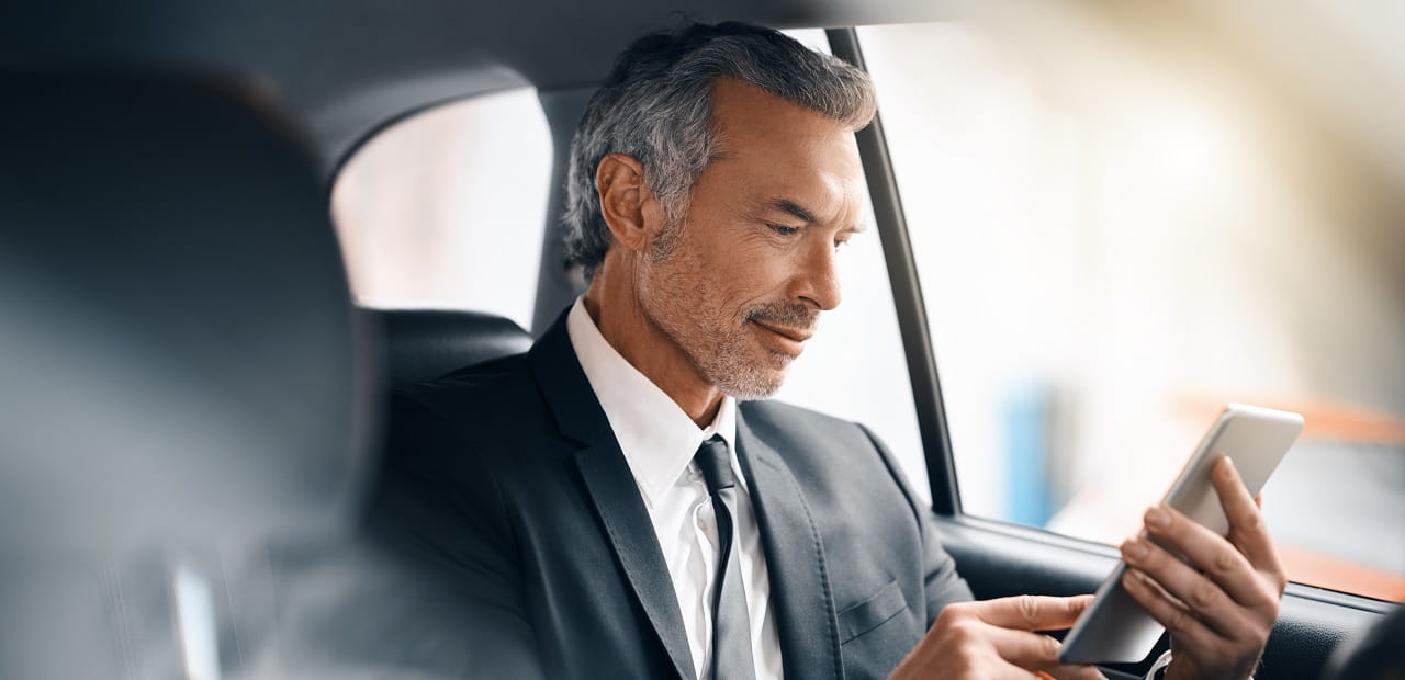 A business professional riding in a vehicle and looking at their phone