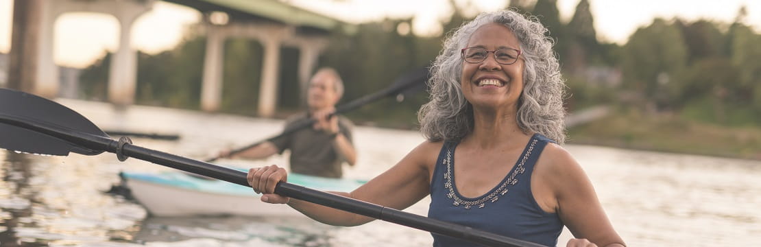 A smiling woman kayaking with her husband