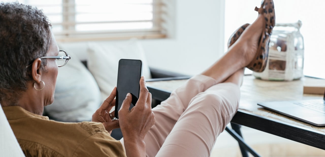 A woman relaxes with her feet up on a table, scrolling on her phone