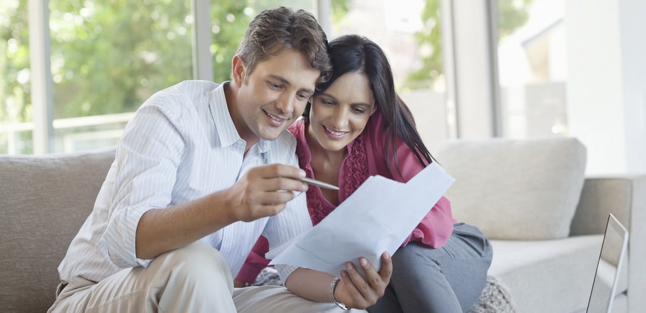 Couple reviewing documents on their couch at home.