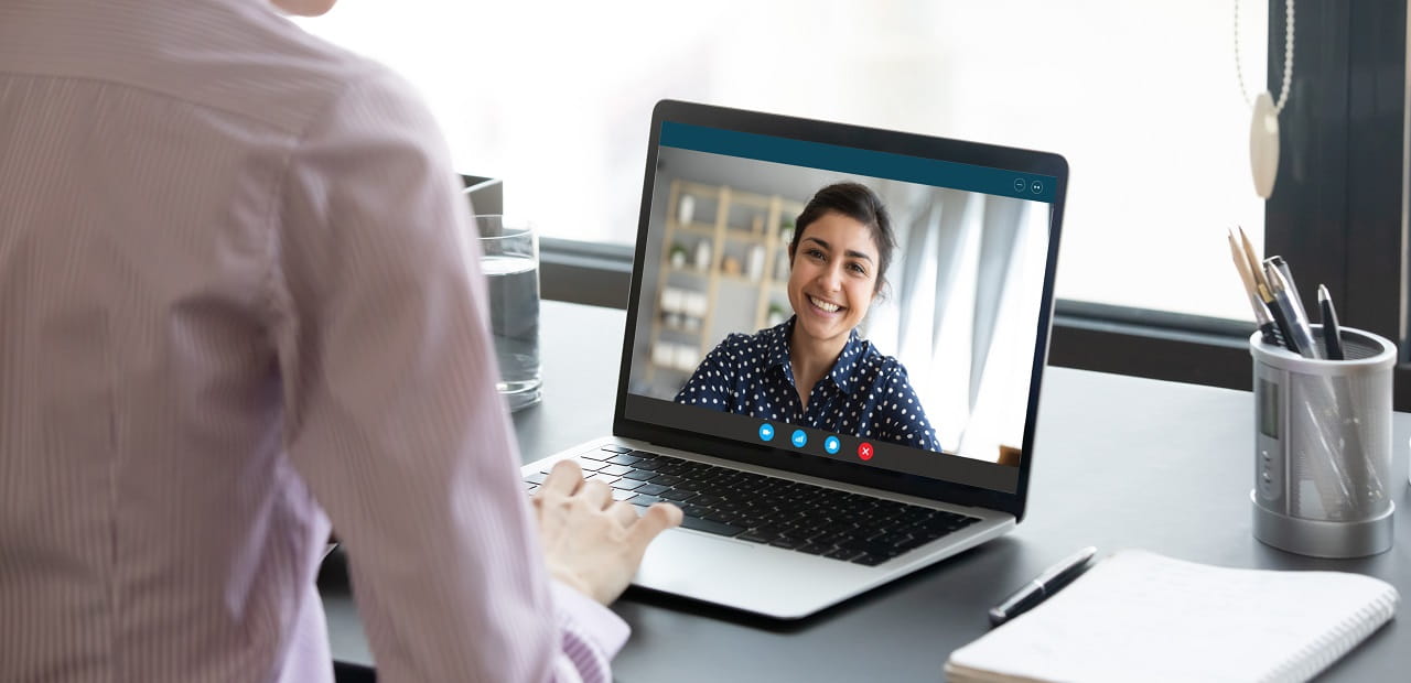 A young professional woman appears on a laptop screen as she attends a virtual meeting