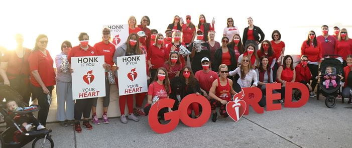 Raymond James associates and Tampa Bay community members wear red and hold "Go Red" and "Honk if you love your heart" signs