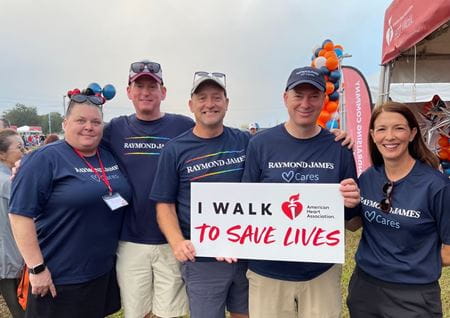Five walkers in navy Raymond James shirts pose with a banner that says "I walk to save lives"
