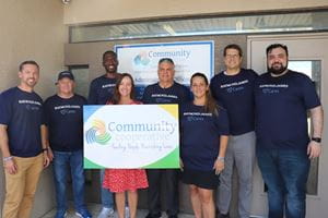 Associates pose with community cooperative sign