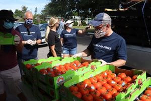 Associates load tomatoes and other food items into the trunk of a car
