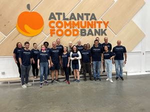 Atlanta associates smile together in front of the Atlanta Community Food Bank sign and peach logo