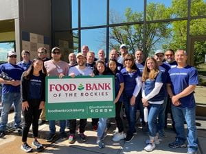 A group of Denver associates poses together with a Food Bank of the Rockies sign