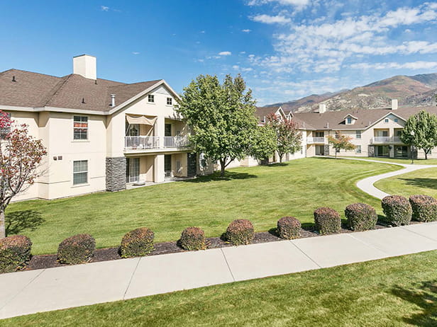 Apartment buildings with sidewalk in front lined by shrubbery